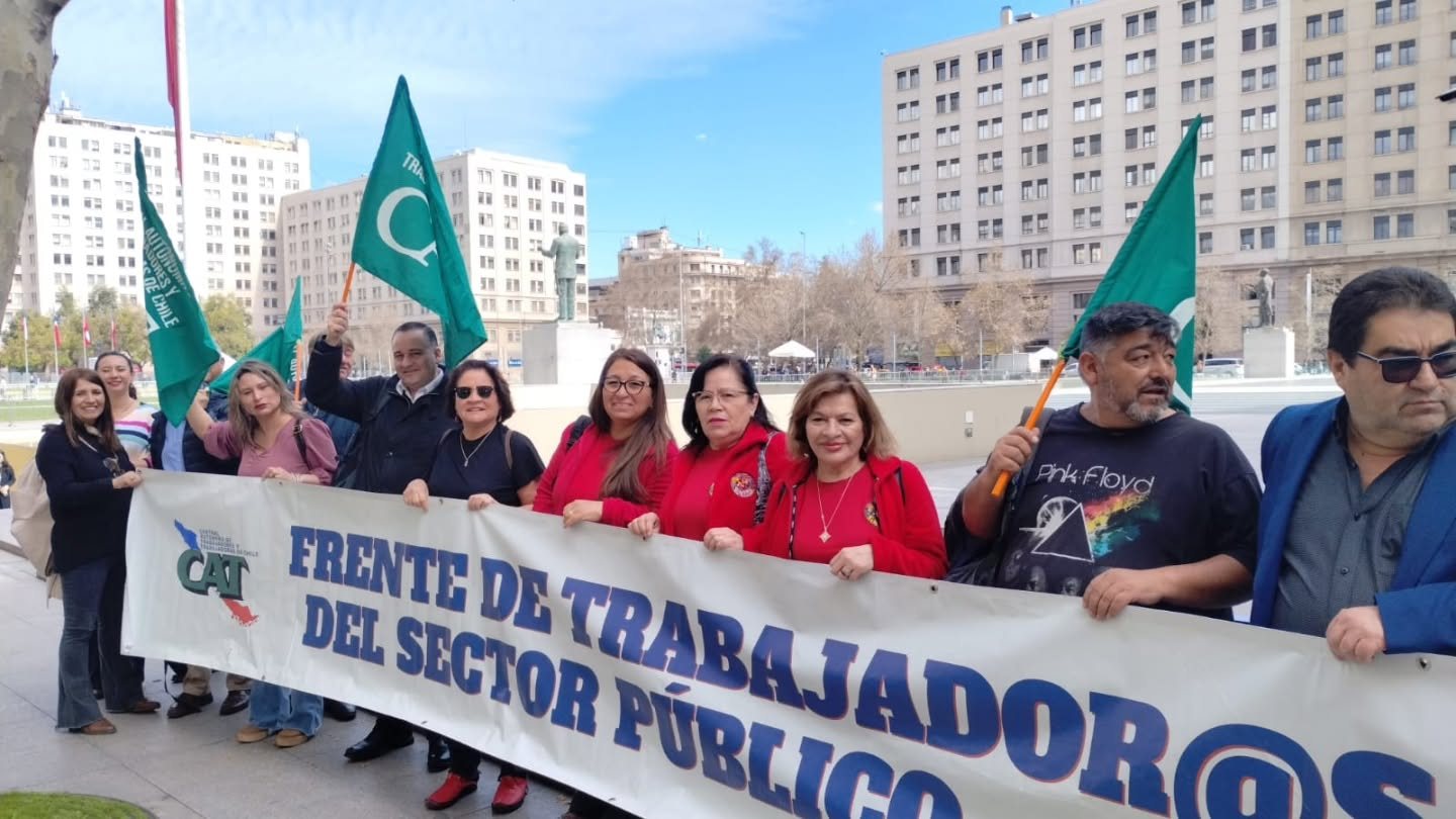 Dirigentas y dirigentes de la CAT, con banderas verdes de la central, sostienen un lienzo del Frente de Trabajador@s del Sector Público en el centro cívico de Santiago